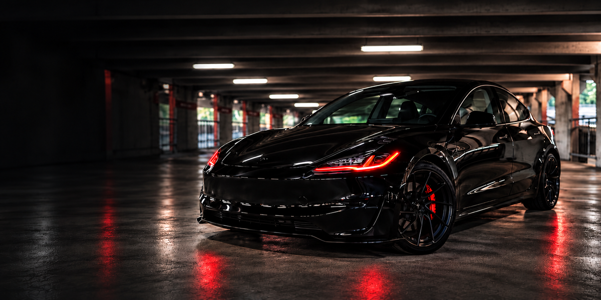 Black Tesla Model 3 with red accent lighting in a garage
